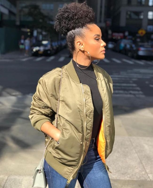 Woman wearina jacket and hoop earrings with curly puff