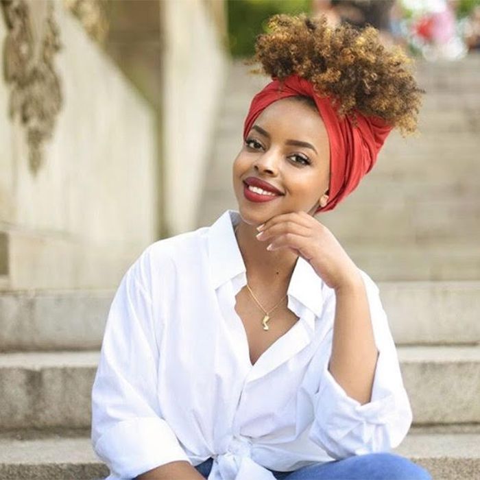 African-American woman sitting down smiling with a red headwrap