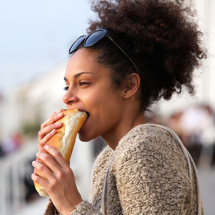 Curly hair woman eating a sandwich