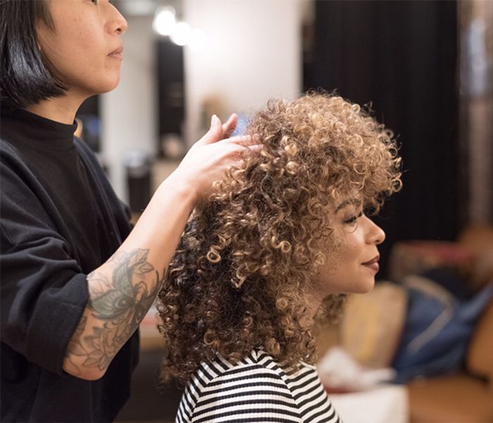 Hair stylist doing a woman with curly hair hair