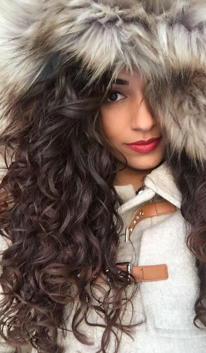 Woman with curly brown hair wearing a fur hooded jacket