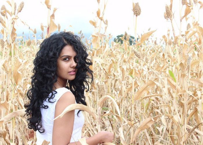 Women with wavy hair walking through field of corn