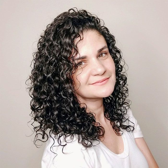 Brazilian woman with curly hair showing how her hair looks after she sat under the dryer