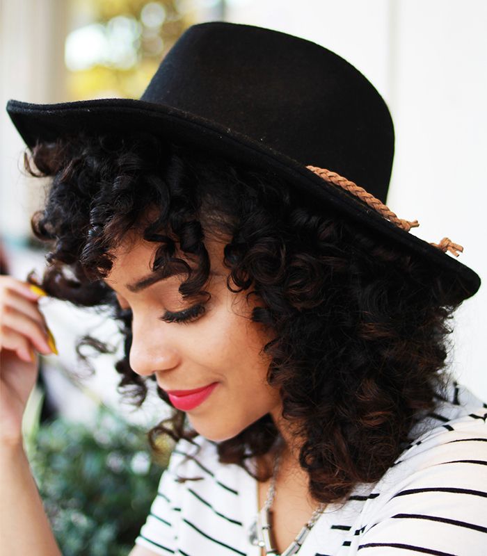 Woman with curly hair wearing a black hat