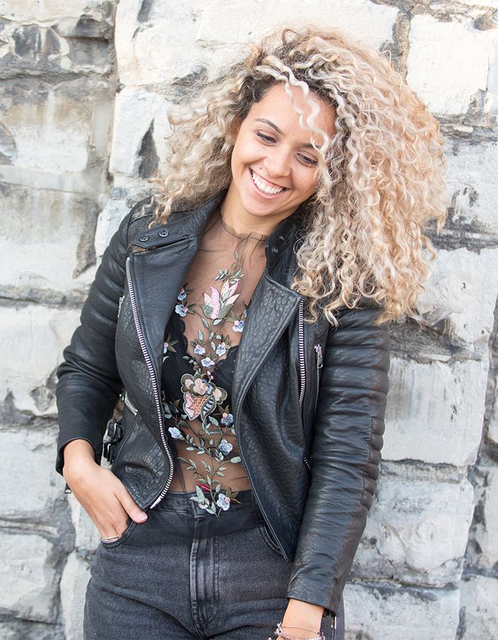 Woman with blonde curly hair wearing a leather jacket