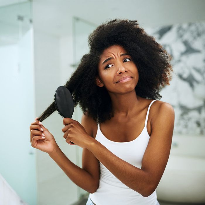 Uma mulher afro-americana escovando o cabelo encaracolado na casa de banho