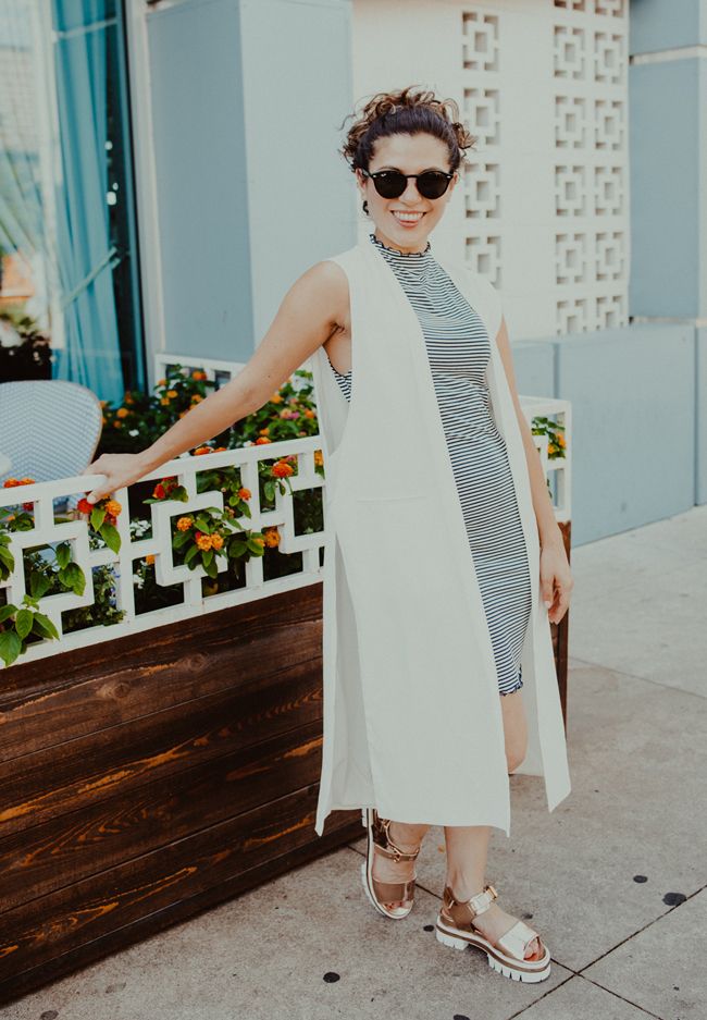 girl wearing white duster jacket, striped dress, platform sandals