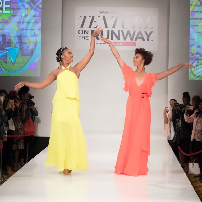 two black models in long neon gowns walk the runway en pointe in ballet shoes Naturally Curly