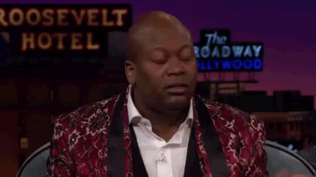 titus burgess on the late late show Actor Titus Burgess leans back and flaps his hands in shock.