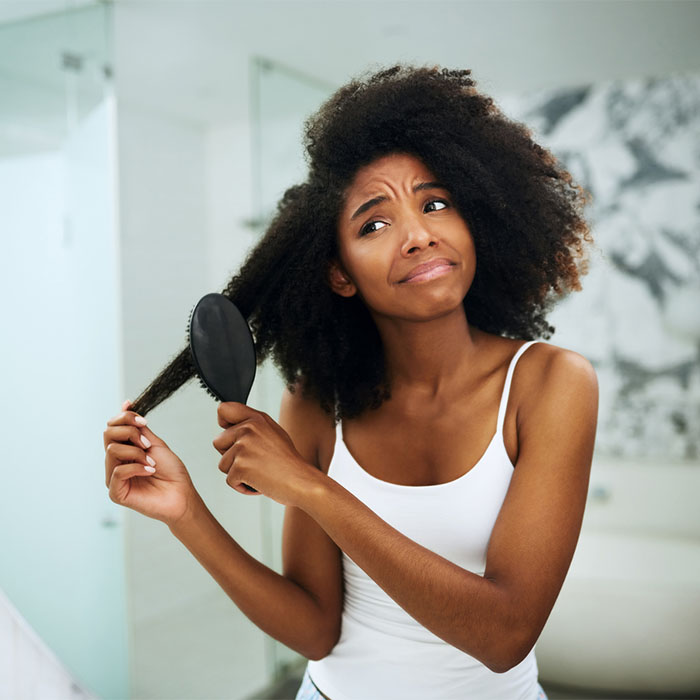 woman detangling curly hair to stop matting